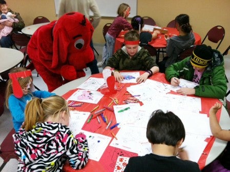 Clifford looks on as children color with crayons.