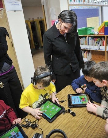 Commissioner Brenda Cassellius of the Department of Education looks over the shoulders of Woodson Kindergarten students using iPads. 