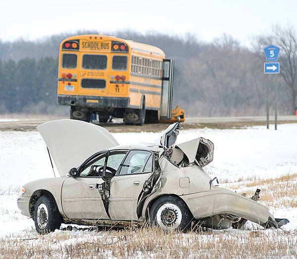 The remains of a four-door car sits in the south ditch of Highway 56 just past the intersection with County Road 5 after colliding with the above bus Wednesday afternoon. Eric Johnson/photodesk@dailyherald.com