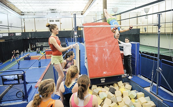 Members of the Austin gymnastics team work out above a foam pit on bar form at the YMCA. In recent years,  the gymnastics program has progressed by leaps and bounds to become one of the best in Minnesota. -- Eric Johnson/Austin Daily Herald