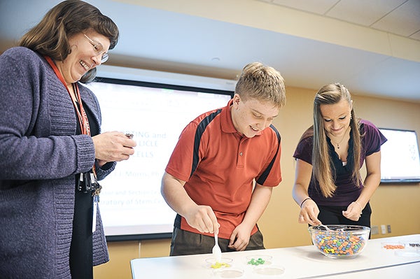 Sophomores Nate Kruger and Kylah Miller take part in an exercise that uses M&Ms to represent cell sorting in helping students understand some of the technology The Hormel Institute uses, as Dr. Rebecca J. Morris times. Morris is a professor and section leader in the laboratory of stem cells. Eric Johnson/photodesk@austindailyherald.com
