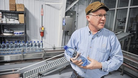 Kevin Brinkley, owner of Artesian Fresh, talks about the bottling process during a tour of the business east of LeRoy on Highway 56.