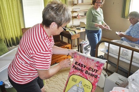 Volunteer Cheryl Dunlap puts a price sticker Wednesday on items in one of the bedrooms at the late Carol Landgraf's house. The items will be up for sale at an estate sale at the end of the month.