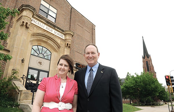 Pacelli vice president Mary Holtorf and Randy Kramer stand in front of Pacelli High School with St. Augustine's Church in the background. The two are co-chairs of Pacelli's 100 Year Committee culminating with their all-school reunion in August. Eric Johnson/photodesk@austindailyherald.com