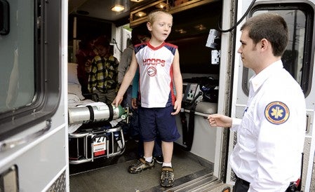 Sumner Elementary first-grader Trenton Whiteaker talks to Gold Cross paramedic Alex Keefe what he thinks about the inside of the ambulance Wednesday afternoon. The paramedics were there to talk to students about keeping the community safe as part of the school's Community Helper curriculum. Eric Johnson/photodesk@austindailyherald.com