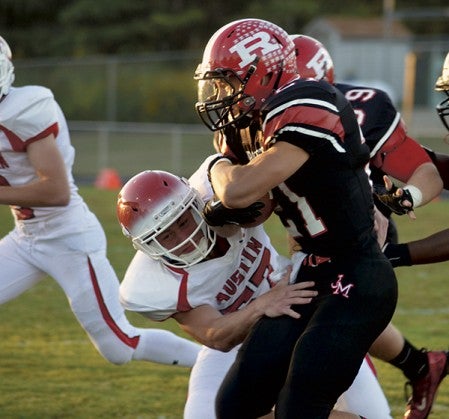 Austin's Devin Klapperick tries to bring down Rochester John Marshall's Jason Rieke in the Packer's 42-22 loss in Rochester Friday. -- Rocky Hulne/sports@austindailyherald.com