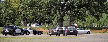 Police gather around a vehicle of a man who they chased behind Marcusen Park in 2012. -- Herald file photo