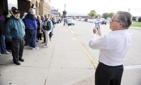 Dick McIntosh takes a picture of the line of people waiting to buy Veldman and Friends tickets that extends far to the east Saturday morning. Eric Johnson/photodesk@austindailyherald.com
