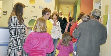Apple Lane Child Care Center employee Lisa Sathre helps a family navigate the new 17,000-square-foot facility during Apple Lane’s open house Wednesday night.