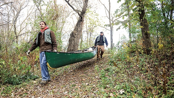 Kris Alvarez, front, and Joe McCarthy carry a canoe to the shore of the Cedar River Wednesday morning. -- Eric Johnson