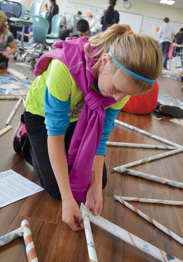 Addie Ross tapes part of a geodesic dome at I.J. Holton Intermediate School Friday. All Holton sixth-graders helped build a dome as part of an engineering unit.  Trey Mewes/trey.mewes@austindailyherald.com