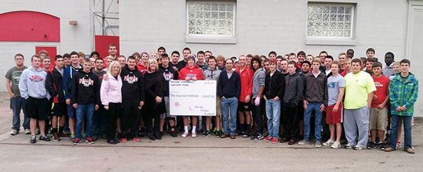 Austin High School’s football team present a nearly $1,660 donation to The Hormel Institute in support of its world-renowned breast cancer research. Money was raised through the team’s second annual “Pink Out Night” game Oct. 16 against Mankato East. Gail Dennison, Director of Public Relations & Development, and Dr. Yibin Deng, one of the Institute’s section leaders researching breast cancer, accepted the donation from the team and Bonnie Kilpatrick, the fundraiser’s leader from the football booster club. The gift will count toward the final Paint the Town Pink fundraising total in February 2014. -- Photo provided