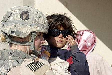 Spc. Taryn Emery, attached to 2nd Battalion, 136th Infantry Regiment, holds a local girl who tries on Emery’s ballistics glasses during a combined humanitarian, medical, school and hygiene engagement operation in Qaryat Al Majarrah, Iraq. U.S. Marine Corps photo by Lance Cpl. Ryan Busse 