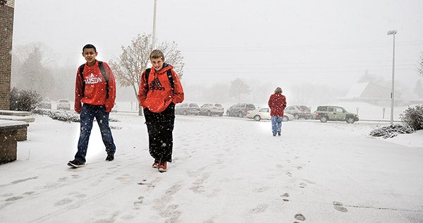Austin Middle School students Riley Retterath, right and Roland Veraza head into the school through falling snow Monday morning. Eric Johnson/photodesk@austindailyherald.com