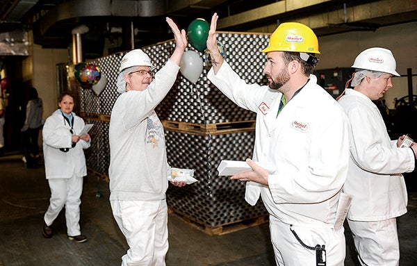 Chad Brand, production supervisor in marinated meats, gives Jim Bartlett a high-five as he hands out profit-sharing checks Wednesday morning at the Hormel plant. -- Eric Johnson