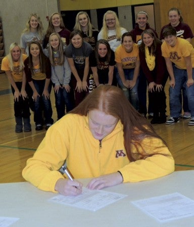 Hayfield senior Dani Wagner signs her national letter-of-intent to play softball at the University of Minnesota with her Hayfield teammates looking on in Hayfield Gym Wednesday. -- Photo provided by Rachel Masching