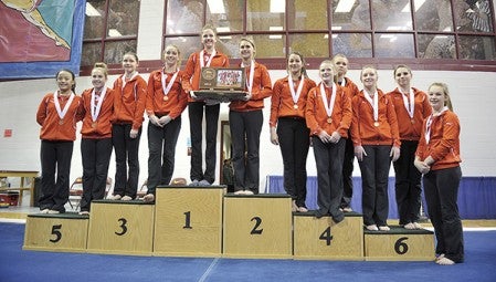 The Austin Packers stand on the podium after being awarded their third-place team trophy at the Minnesota State Gymnastics Meet in Februrary at the Sports Pavilion of the University of Minnesota. -- Herald file photo