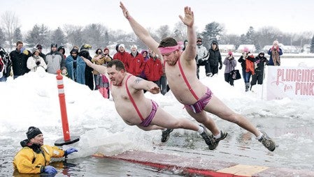 Chad Thomas, right, and Jeremy Olson layout on their jump into East Side Lake Saturday for Plunging for Pink, part of Paint the Town Pink.  Eric Johnson/photodesk@austindailyherald.com