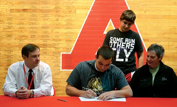 Austin senior Andrew Hagan signs his national letter-of-intent to play football at Division II Southwest Minnesota State University in Austin High School Wednesday. Hagan will also compete on the SMSU track and field team. Hagan signed with is dad Dewey, his mom Mary and his brother Patrick on hand. -- Rocky Hulne/sports@austindailyherald.com