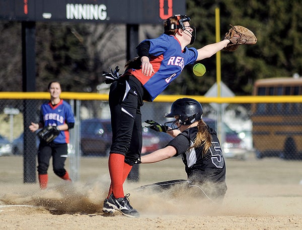 Blooming Prairie's Lizz Willert slides under the reach of Southland's Macy Klaehn as the ball gets past her in the first inning Friday in Blooming Prairie. Eric Johnson/photodesk@austindailyherald.com