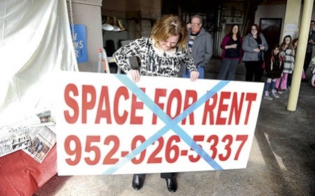 Austin Area Commission for the Arts executive director Jennie Knoebel holds up the “Space for Rent” sign that hung in the window of the bank building downtown. Knoebel and the AACA announced a rental agreement with building owner Patrick Bradley Thursday. 