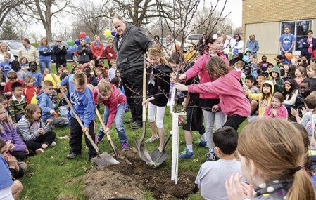 Banfield principal Jeff Roland helps students shovel dirt onto a freshly planted tree in celebration of the Banfield Elementary’s 60th anniversary Wednesday morning. Trey Mewes/trey.mewes@austindailyherald.com