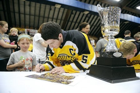 Austin Bruins Josh Bretner signs an autograph for Jakob Loverink next to the NAHL Central Cup during a welcome home Wednesday night in Riverside Arena. 