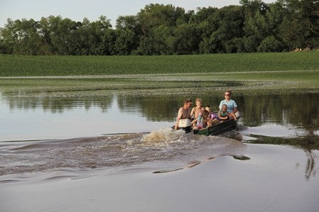 Greg and Billie Braaten boat Friday night with their children, Cody, 6; Addison, 3; Riley, 13; and Max, 2, in their flooded rural Austin field along Highway 251 partway between Maple Island and Highway 218. The Braatens said they were trying to make the most of the recent floodwater and estimated the water was about 4 feet deep in their cornfield. Greg farms more than 50 acres and estimated he lost at least 30 percent of his crop. This wasn’t the first time the field has flooded, as Billie recalled boating in the field in the mid-2000s.  Jason Schoonover/jason.schoonover@austindailyherald.com