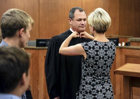 Tami Kritzer cinches the robes of her husband Jeffrey who was sworn in as a Mower County judge Friday afternoon at the Jail and Justice Center.  Eric Johnson/photodesk@austindailyherald.com
