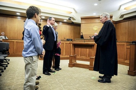 Judge Fred Wellman swears in Jeffrey Kritzer, standing with his family, Friday afternoon at the Jail and Justice Center.  Eric Johnson/photodesk@austindailyherald.com