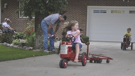 Allison Prescott, 5, looks behind as her brother George, 3, rides a mini-tractor toward her at the 2014 Breakfast on the Farm in rural Austin Saturday. Trey Mewes/trey.mewes@austindailyherald.com