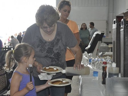 Rita Honegraaf helps her 5-year-old granddaughter Gabriella Tangren pour syrup on her pancakes.