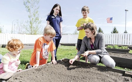 Hy-Vee nutritionalist Jen Haugen demonstrates how to plant spinach seeds during the planting of the One-Step Garden in May. Herald file photo