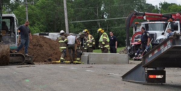 Austin firefighters pull out a worker from under Sixth Street Southwest Tuesday near the former site of American Mat Company. Two workers were trapped when a wall underground fell down. Trey Mewes/trey.mewes@austindailyherald.com
