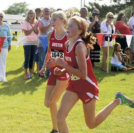Austin's Paiton Schwab, right, and Abby Lewis sprint side by side down the stretch at the Austin cross country invite in Meadow Greens golf course Tuesday. -- Rocky Hulne/sports@austindailyherald.com