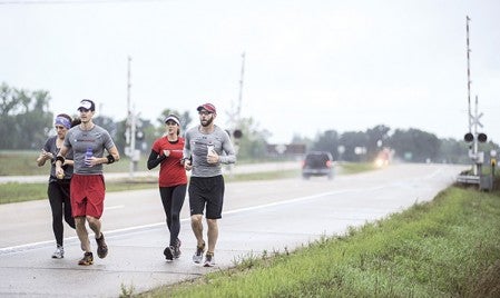 Kelly Nesvold, right, runs south on Highway 218 toward Austin early Saturday morning along with his wife Danielle Nesvold, from left, Todd Dube and Corinne Neitzell as they near the completion of a 50-mile test run of his upcoming 100-mile run for his 100M4HUNGER hunger awareness run.  Photos by Eric Johnson/photodesk@austindailyherald.com