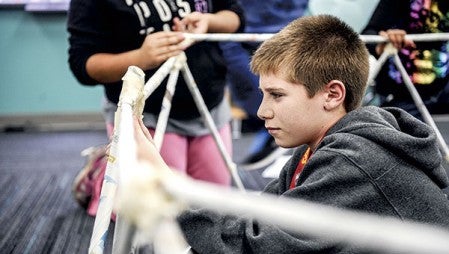 I.J. Holton student Elijah Hemann tapes a joint as his group builds a structure out of newspapers Thursday at the school.  Photos by Eric Johnson/photodesk@austindailyherald.com