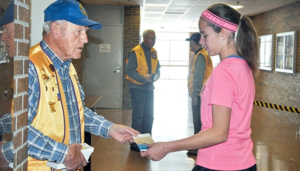 Seventh-grader Brittney Wolter takes a Constitution booklet from Chairman of the Liberty Day Committee Howard Nepp as students gathered for an assembly Wednesday afternoon. -- Jenae Hackensmith/jenae.hackensmith@austindailyherald.com