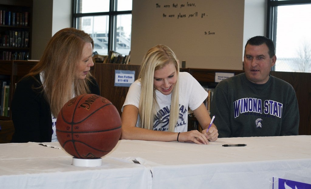 Blooming Prairie's Madison Worke signs her national letter of intent to play basketball at Winona State University with her parents Mary Worke and John Worke at the Blooming Prairie High School Library Wednesday. -- Rocky Hulne/sports@austindailyherald.com