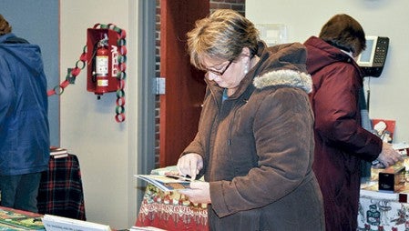 Tricia Wiechmann of Austin looks at books for Christmas presents at the opening of the book fair Thursday evening. The fair is in the small meeting room at the Austin Public Library and will go through Saturday. Jenae Hackensmith/jenae.hackensmith@austindailyherald.com
