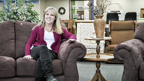 Lynn Nuckolls sits on a couch for sale at the new ReStore. She recently took over the manager position at the store which recently moved to a new location. Jenae Hackensmith/jenae.hackensmith@austindailyherald.com