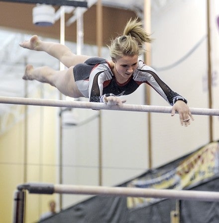 Austin's Rachel Quandt twists to grab the bar during her performance on the uneven parallel bars Friday night at the YMCA. Eric Johnson/photodesk@austindailyherald.com