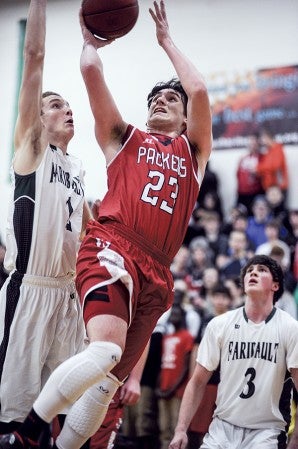 Austin's Nik Gasner puts up a shot inside against Faribault's Kade Hart in the first half Friday night in the Packer Gym. Eric Johnson/photodesk@austindailyherald.com