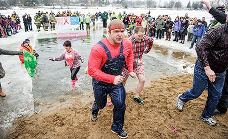 Members of the group Timber Rush from the water after jumping into East Side Lake during Saturday afternoon’s Polar Plunge.