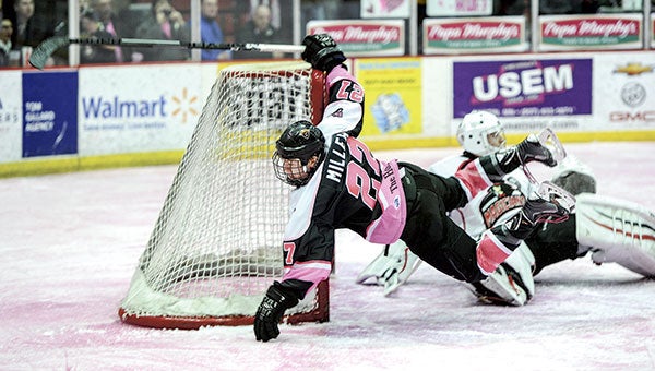 The Austin Bruins Jade Miller goes airborne after taking a shot on goal in the second period against the Minnesota Magicians Saturday night during the Paint the Rink Pink at Riverside Arena. Photos by Eric Johnson/photodesk@austindailyherald.com