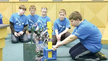 Braden Greibrok, 12, (right) holds blocks steady as the two I.J. Holton Engineers sixth-grade robotics teams demonstrate their robots to the Austin Public Schools Board at its regularly scheduled meeting Monday evening. The teams each have a driver who directs the robot to stack certain game pieces within a specific time limit.  Jenae Hackensmith/jenae.hackensmith@austindailyherald.com