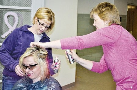 Woodson Kindergarten Principal Jessica Cabeen gets her hair sprayed pink by Administrative Assistant Lisa Bellrichard (left) and teacher Chris Kasak after the kindergarten critters third year of collecting pennies raised more than $1,800 for Paint the Town Pink cancer research. Jenae Hackensmith/jenae.hackensmith@austindailyherald.com