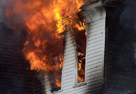 Flames billow out of two windows of a home at 25886 708th Ave. in Manchester Monday afternoon. 