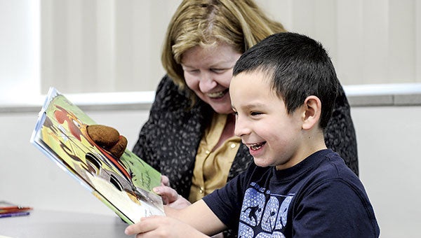 Woodson Kindergarten Center student Enrique Yepez giggles as he reads along with Hormel employee Marianne Pollack Tuesday afternoon. Pollack is part of the company program Helping Hands and is part of a number of employees that read to students once a week for 30 minutes.  Photos by Eric Johnson/photodesk@austindailyherald.com