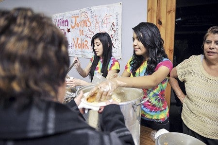 Jazmyne Rodriquez serves up food with her cousin Maria Hernandez, left, at the Jovenes de Valor table at Taste of Nations in 2013 at the Oak Park Mall. The club is an Austin High School club. Herald file photo